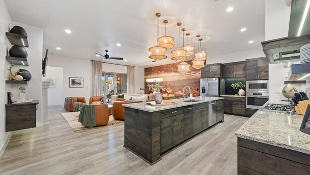 A modern kitchen with a central island, dark wood cabinets, stainless steel appliances, and pendant lighting. - Premier Poolside Location | Private Hot Tub + Fire Pit | Ping Pong | Arcadia #13 (Santa Clara)