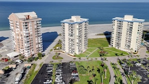 Um hotel na praia com três edifícios altos, um parque de estacionamento e vista para o oceano.