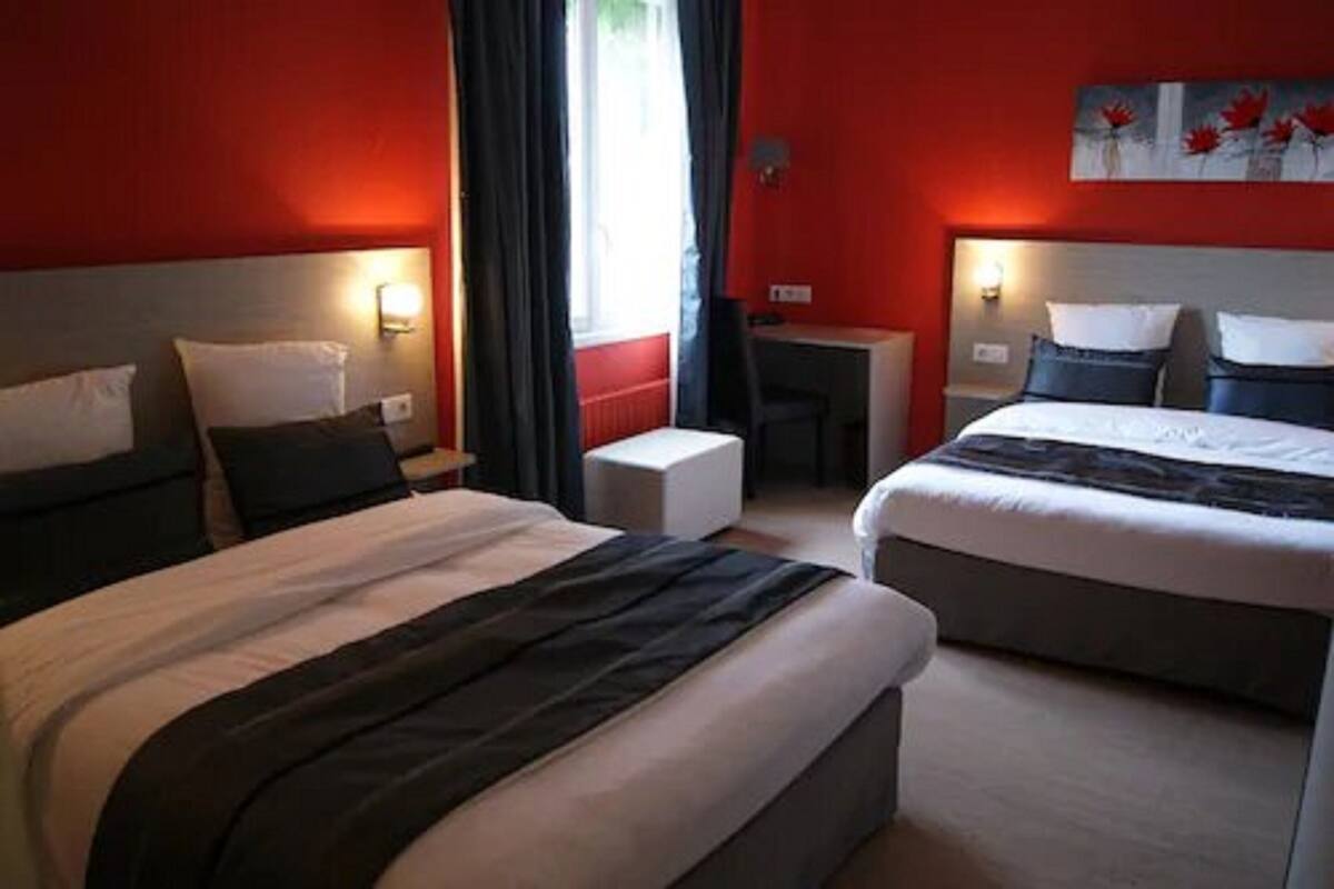 Habitación de hotel con dos camas, un escritorio y una silla.