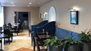 A modern hotel lobby with a seating area, a reception desk, and a large painting on the wall. - Hotel Le Montloire (Montlouis-sur-Loire)