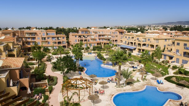 Un complexe hôtelier doté de plusieurs piscines, de palmiers et offrant une vue sur un ciel bleu azur.