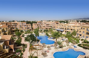 A resort with multiple swimming pools, palm trees, and a clear blue sky.