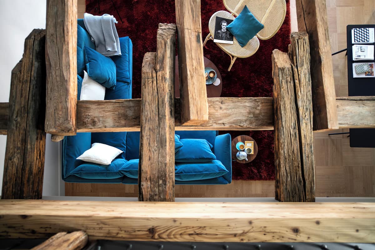 A rustic room with a wooden bed frame, a blue sofa, and a red carpet.
