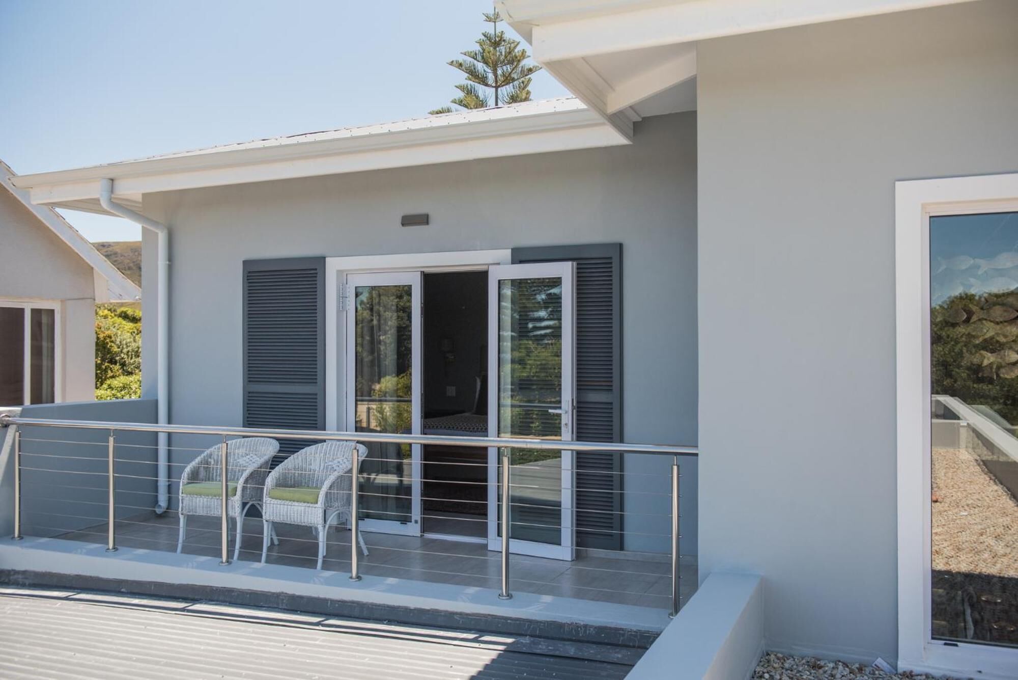 A modern building with a balcony featuring two wicker chairs and a glass door.