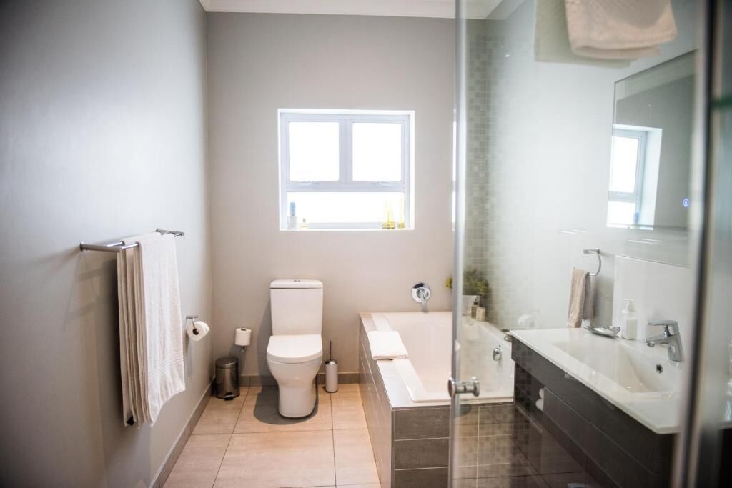 Un baño moderno con inodoro, lavamanos y bañera.