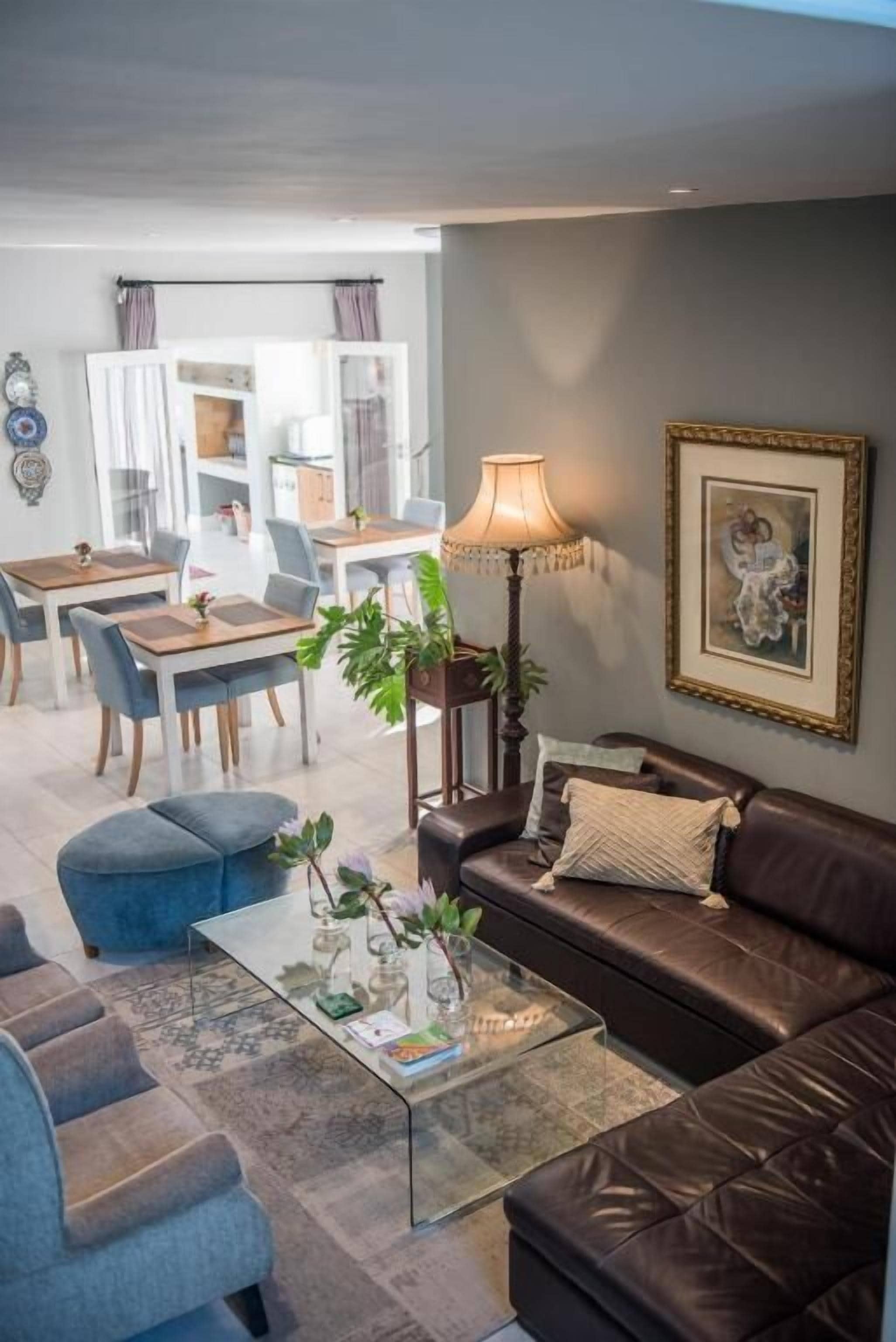 Ein Wohnzimmer mit einem braunen Ledersofa, einem Glastisch und einem Essbereich mit Tisch und Stühlen.