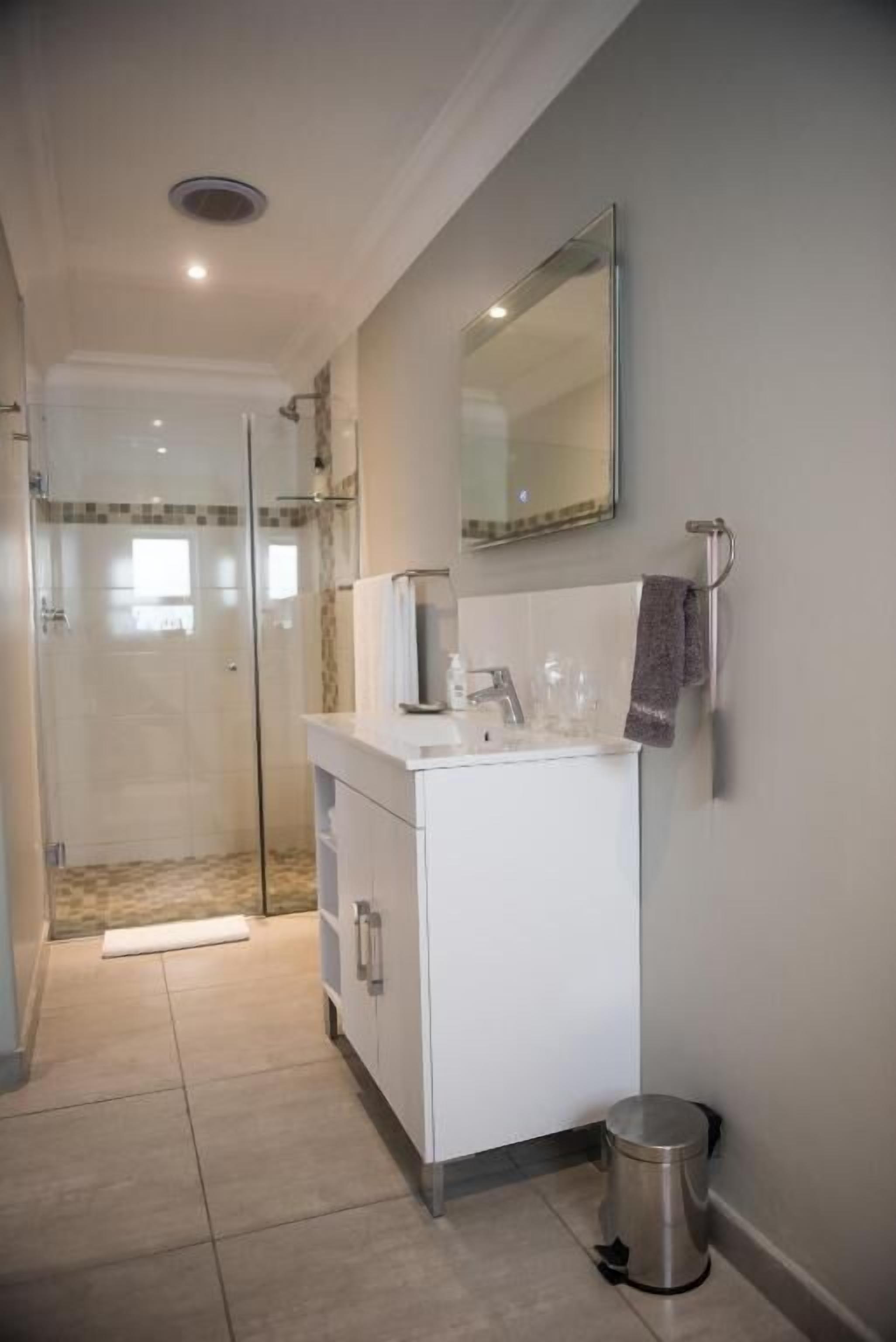 Un baño con ducha, lavamanos y espejo.