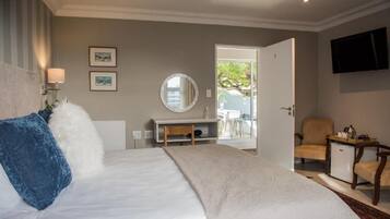 Quarto de hotel com cama, escrivaninha, poltrona, televisão e vista para o exterior.