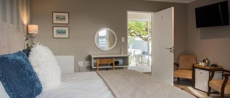 A hotel room with a bed, a desk, a chair, a television, and a view of the outdoors.