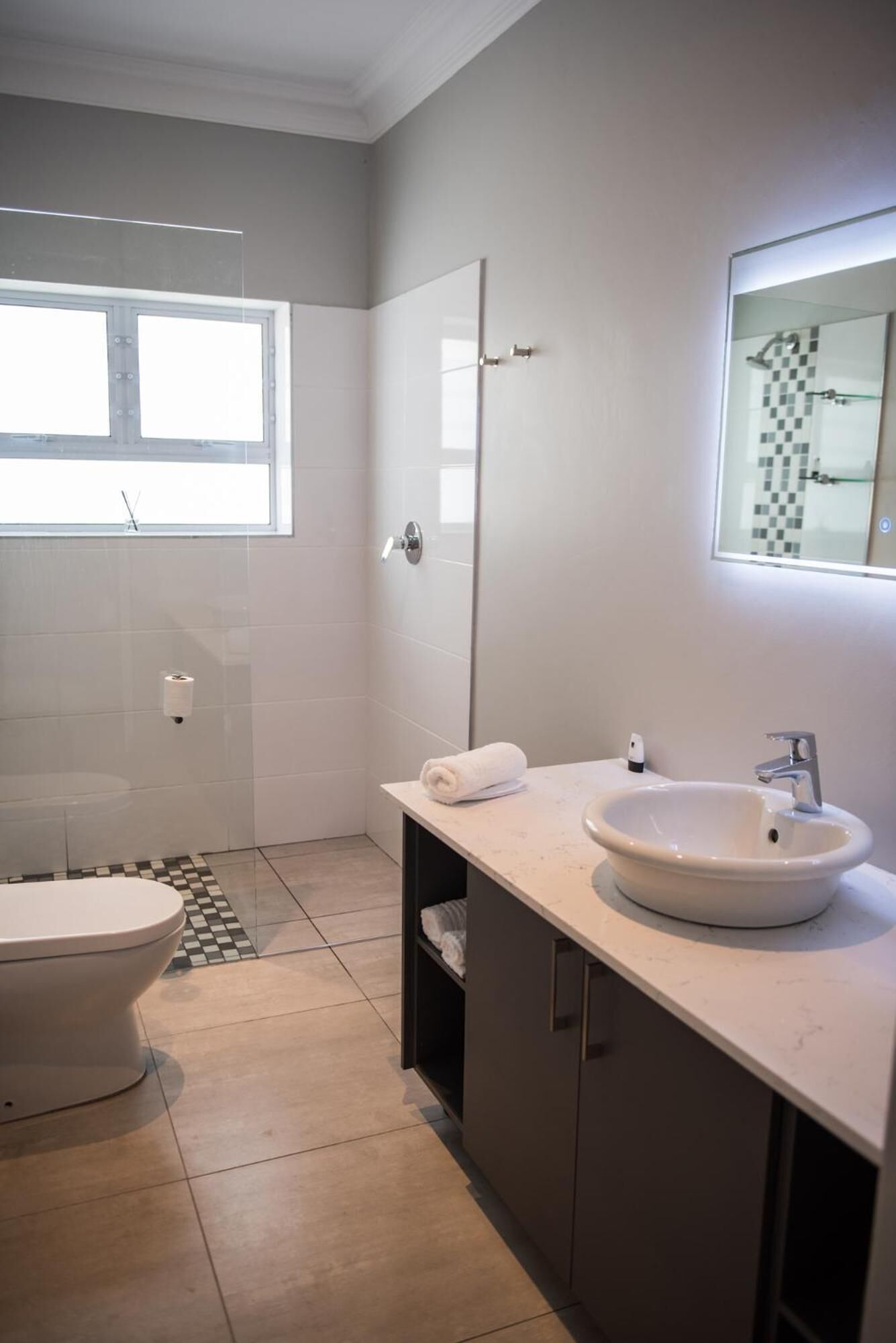 A modern bathroom with a toilet, a sink, and a shower.