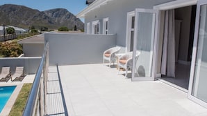 A modern villa with a pool, white wicker furniture, and a mountain view. - The Whale on Main B&B (Hermanus)