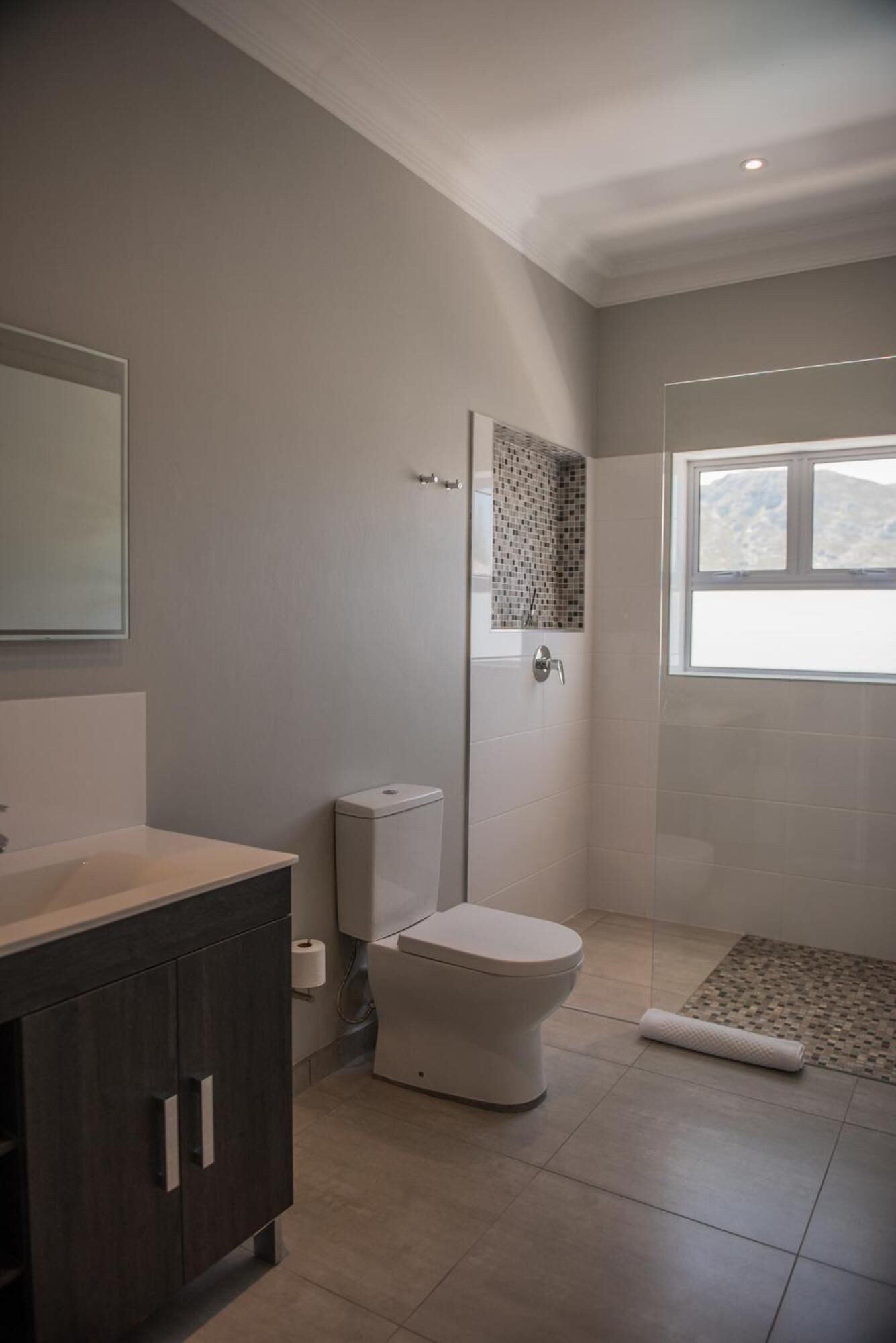 Un baño moderno con inodoro, cabina de ducha y tocador con espejo.
