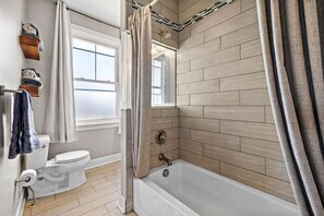 A bathroom with a toilet, bathtub, and a window. - Serene, Smart, Spacious. Near Downtown + Garage (Pittsburgh)