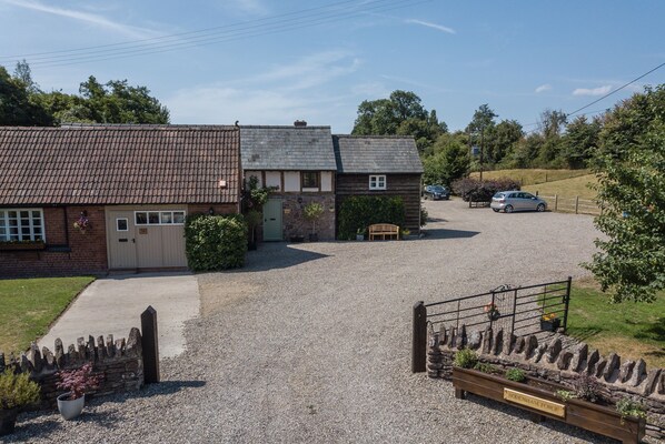 A gravel driveway leading to a house with a wooden gate and a sign that reads "Bodendenham Forge." - Idyllic riverside location (Hereford)