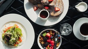 A table set with breakfast items including pancakes, fruit, and coffee.