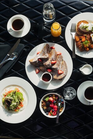 A table set with breakfast items including pancakes, fruit, and coffee.