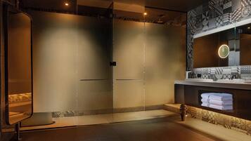 A modern bathroom with a glass shower enclosure, a vanity with a mirror, and a towel rack.