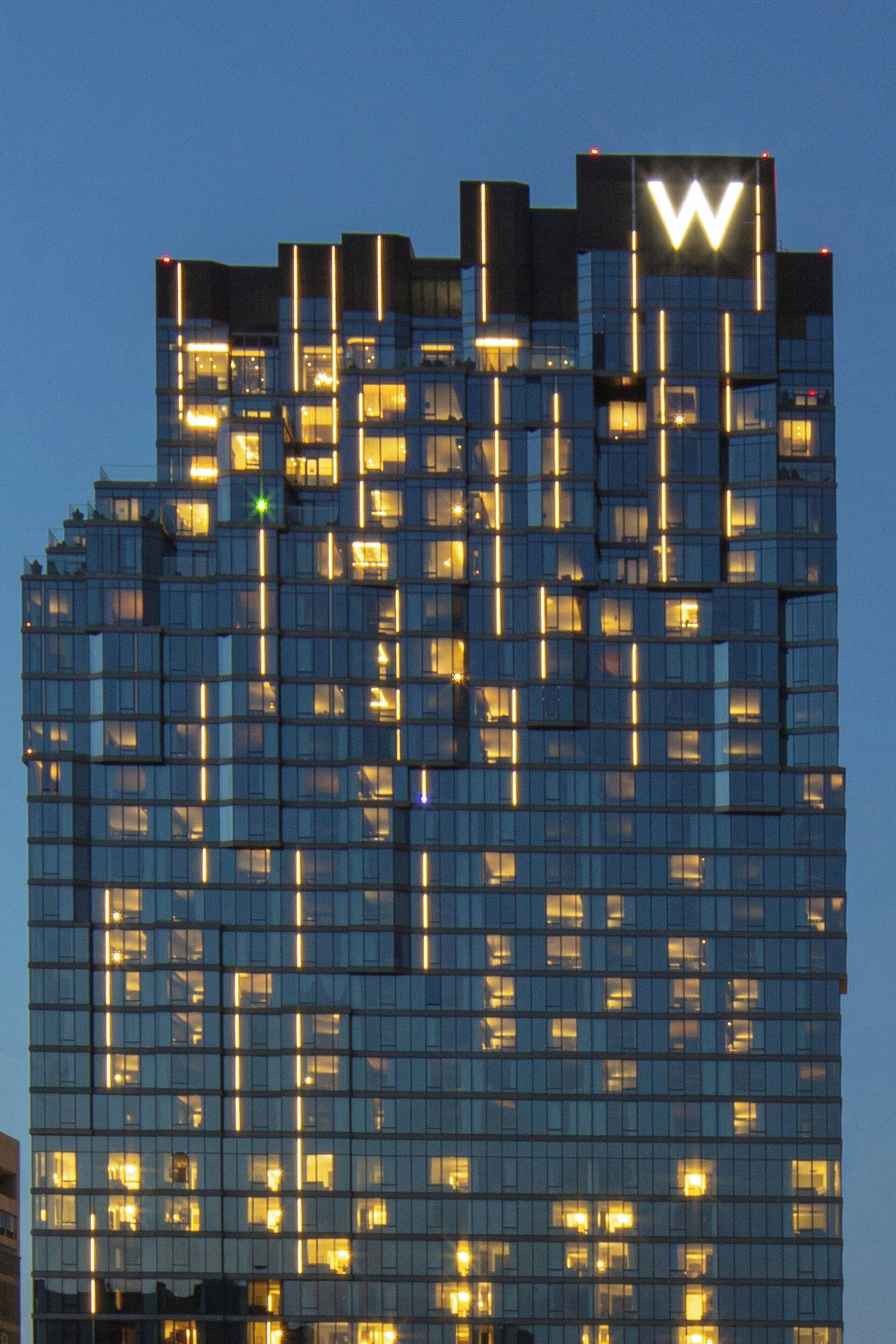 Un moderno edificio de gran altura con un llamativo logo 'W' en la parte superior.