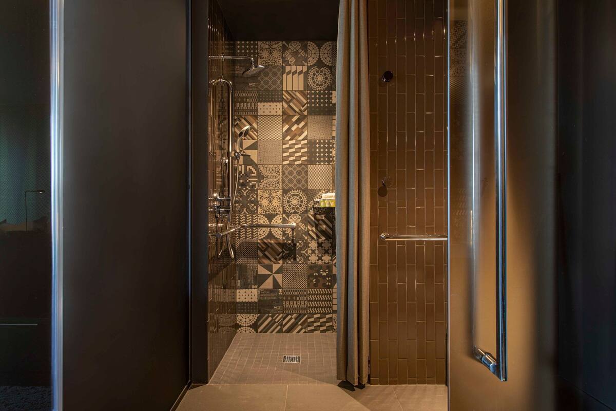 A narrow hallway with patterned tiles leading to a bathroom.