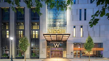 A modern hotel entrance with a prominent 'W' logo, large glass windows, and a well-lit facade.