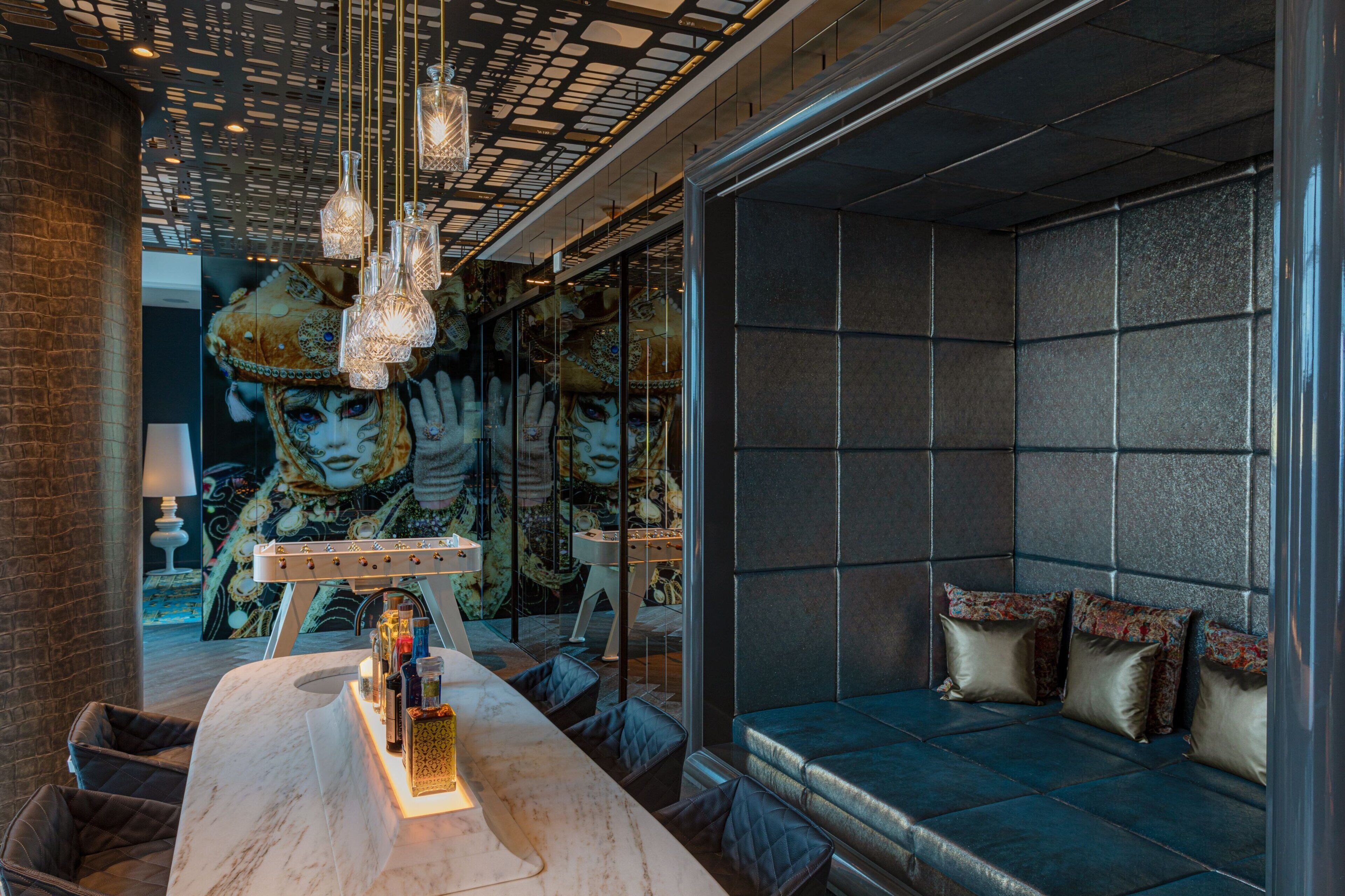 Um interior moderno com mesa de mármore, área de estar com almofadas e iluminação decorativa.