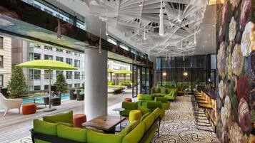 A modern indoor space with green seating, a pool, and a patterned floor.