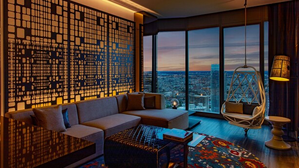 A modern living room with a large window, a decorative wall panel, a sofa, a hanging chair, and a coffee table. - W Philadelphia (Philadelphia)