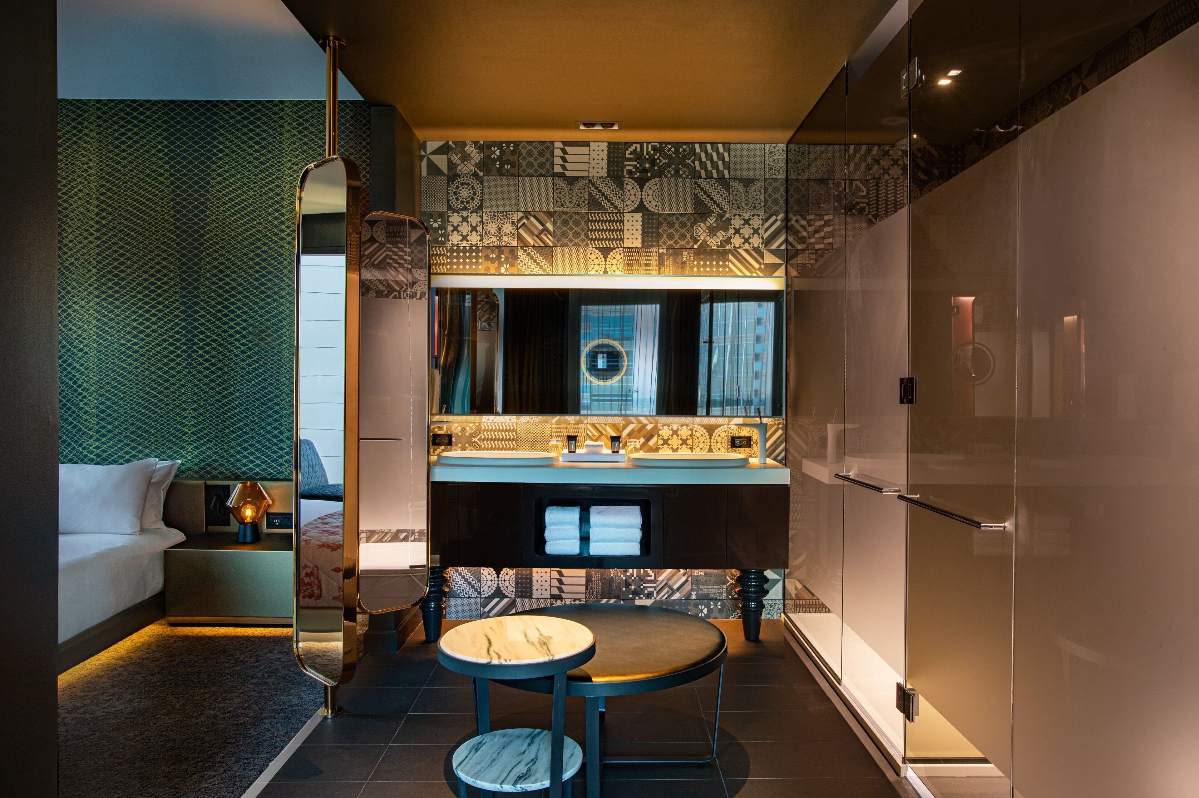 A modern bathroom with a large mirror, patterned tiles, and a vanity with a sink.