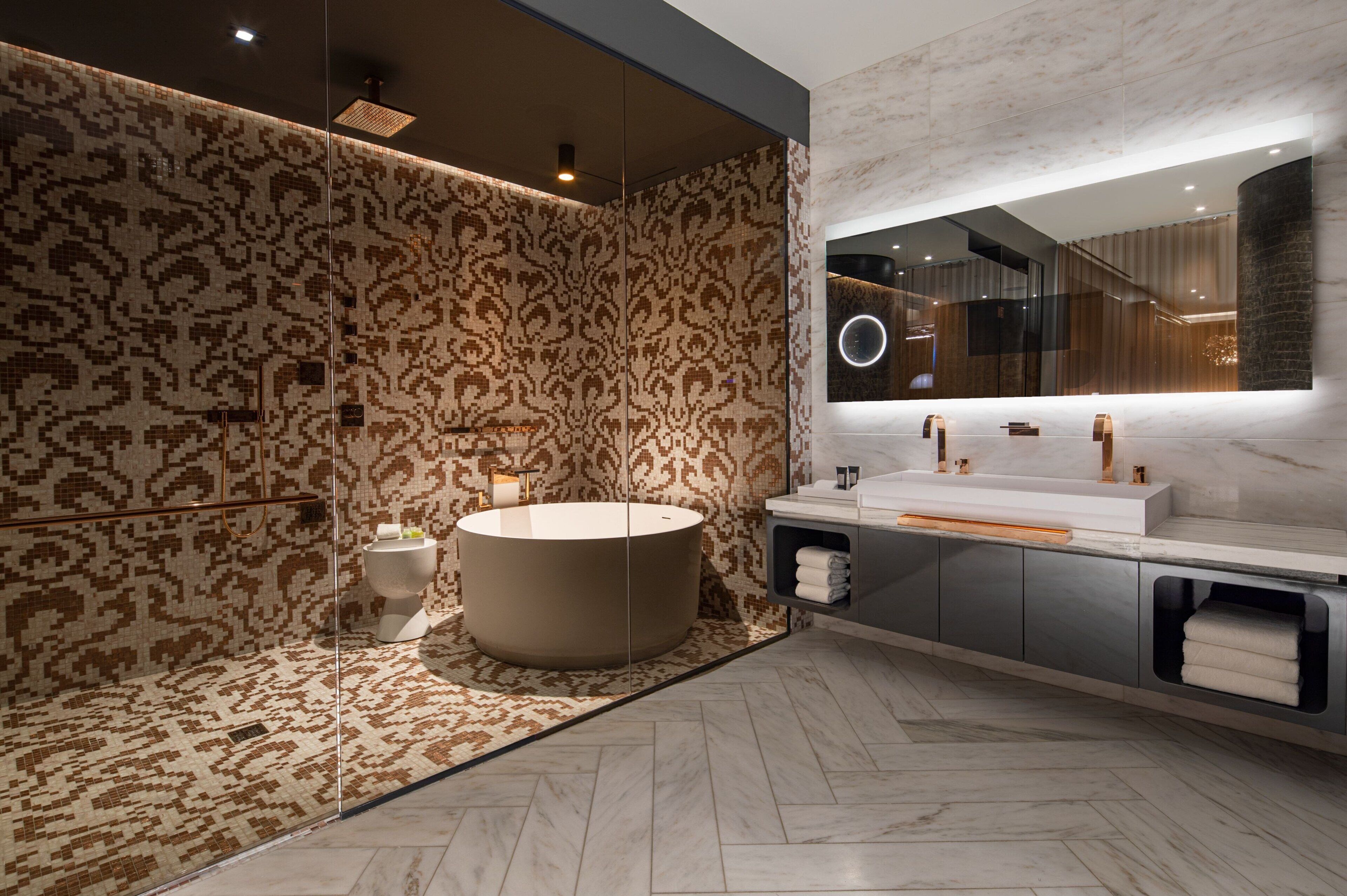 A modern bathroom with a large bathtub, a vanity with a mirror, and patterned walls.