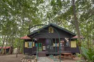 A rustic cabin with a porch, surrounded by trees.