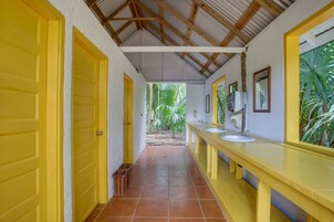 A corridor with yellow doors, a tiled floor, and a long counter with sinks and mirrors.