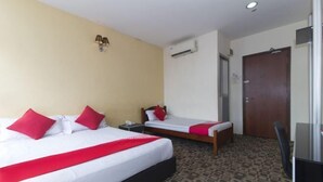 Ein Hotelzimmer mit zwei Betten, einem Schreibtisch, einem Stuhl, einer Klimaanlage und einer Tür.