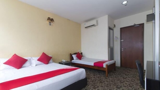 Habitación de hotel con dos camas, un escritorio, una silla, un equipo de aire acondicionado y una puerta.