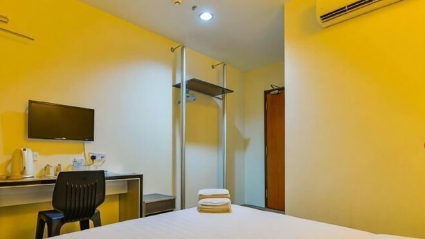 Ein Hotelzimmer mit Bett, Schreibtisch mit Stuhl, Fernseher und Dusche.