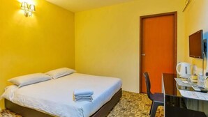 Ein Hotelzimmer mit einem Bett, einem Schreibtisch, einem Sessel, einem Fernseher und einer Tür.