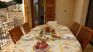 A dining table set with plates, glasses, and a bottle of wine, surrounded by wooden chairs.