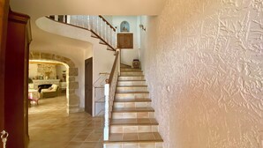 A staircase with a wooden handrail leading to a landing with a vase and a framed picture.