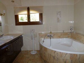 Un baño con bañera, lavabo y ventana.