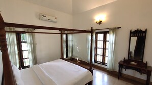 A four-poster bed with a wooden frame, a bedside table with a mirror, and a wall-mounted air conditioning unit. - Rasa Gurukul (Chalakudy)