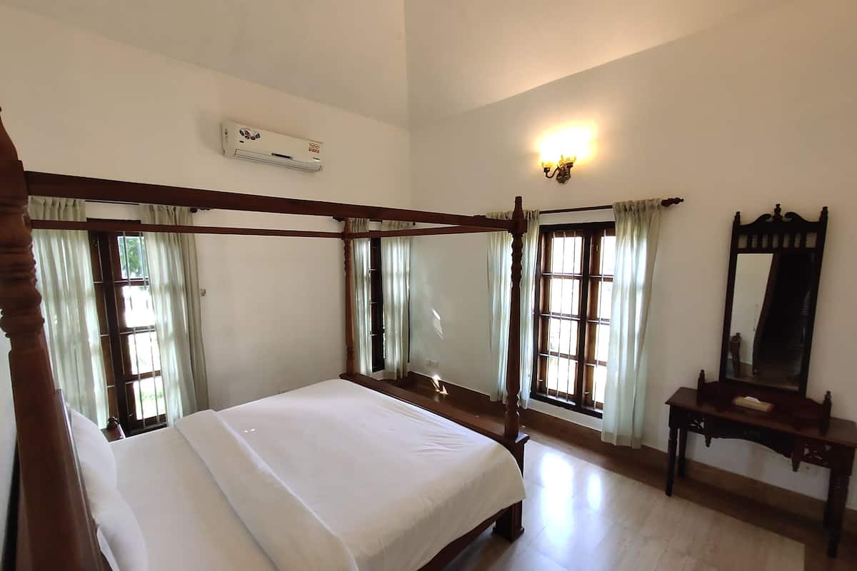 A four-poster bed with a wooden frame, a bedside table with a mirror, and a wall-mounted air conditioning unit.
