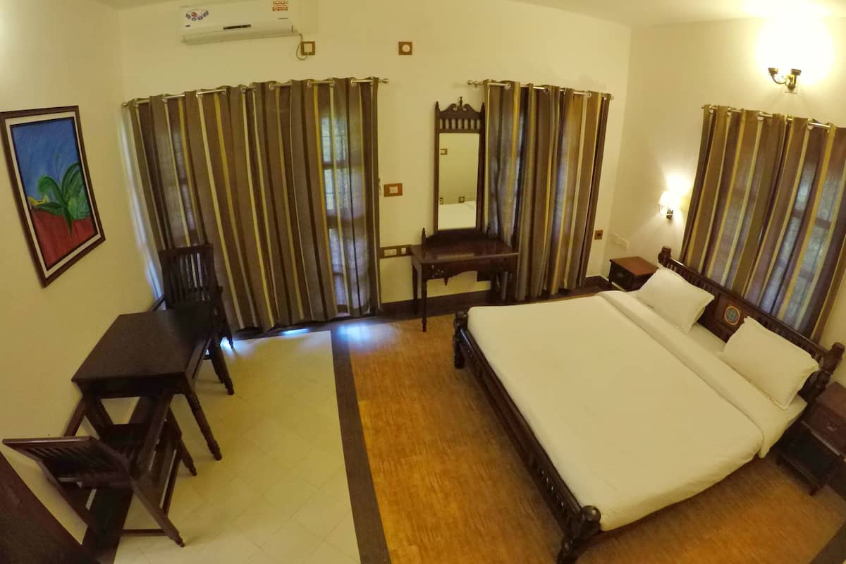 A hotel room with a large bed, a desk, a chair, and a mirror.