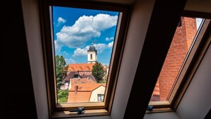 Ventana de tragaluz con vista a una torre de iglesia y edificios circundantes.