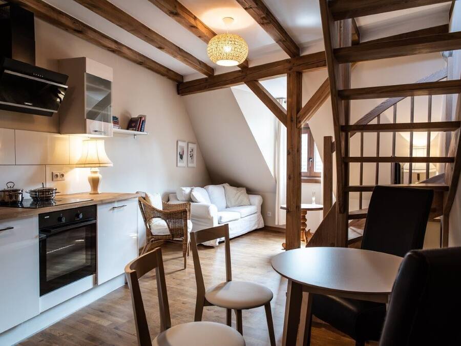 A cozy kitchen with a dining area, wooden beams, and a hanging light fixture.