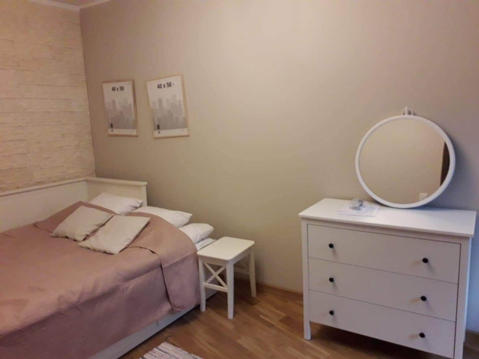 Une chambre à coucher comprenant un lit, une table de chevet, une commode et deux tableaux encadrés accrochés au mur.