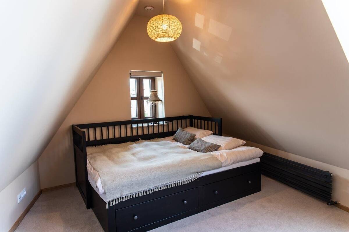 Un dormitorio con una cama negra, una ventana y una lámpara colgante.