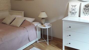 Une chambre à coucher comprenant un lit, une table de chevet, une lampe, une commode et des tableaux encadrés accrochés au mur.