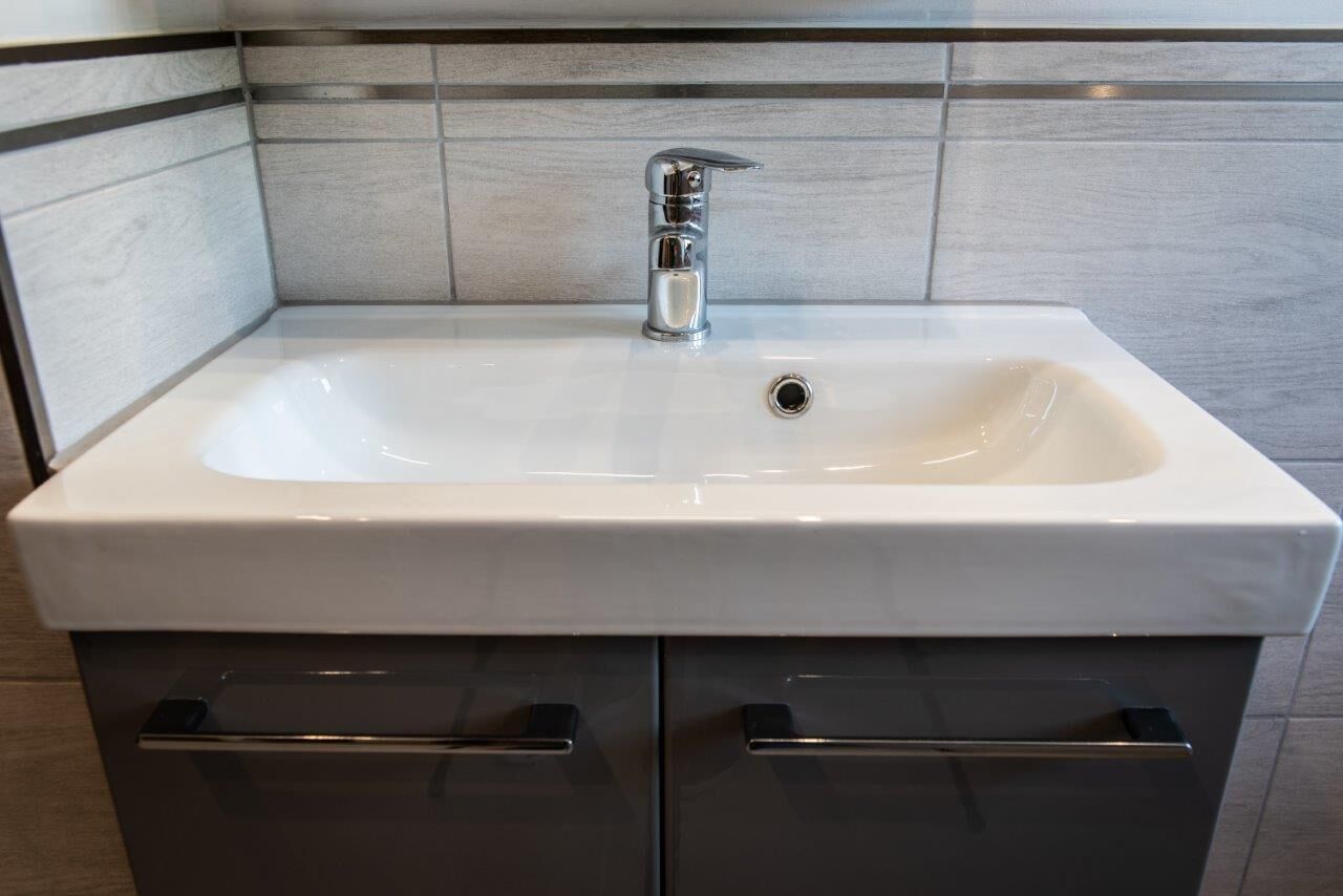 A bathroom with a white sink, chrome faucet, and two drawers below.