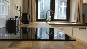 Una cocina moderna con encimera negra, cafetera, hervidor y una botella de detergente.