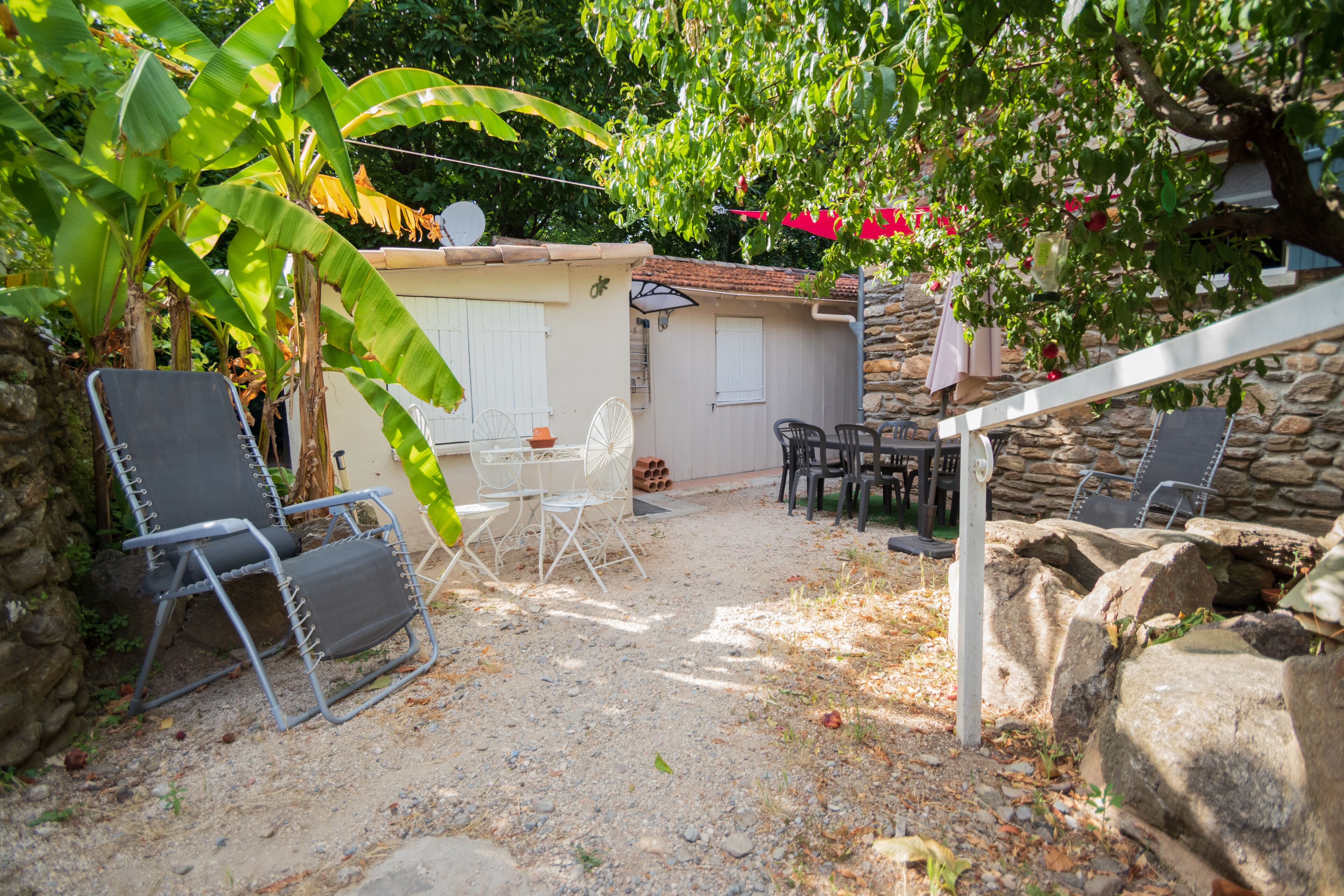 A patio area with stone walls, a white fence, and outdoor furniture including chairs and a table.