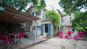Un edificio in pietra con un portico coperto, posti a sedere all'aperto e una scala in pietra che conduce all'ingresso.